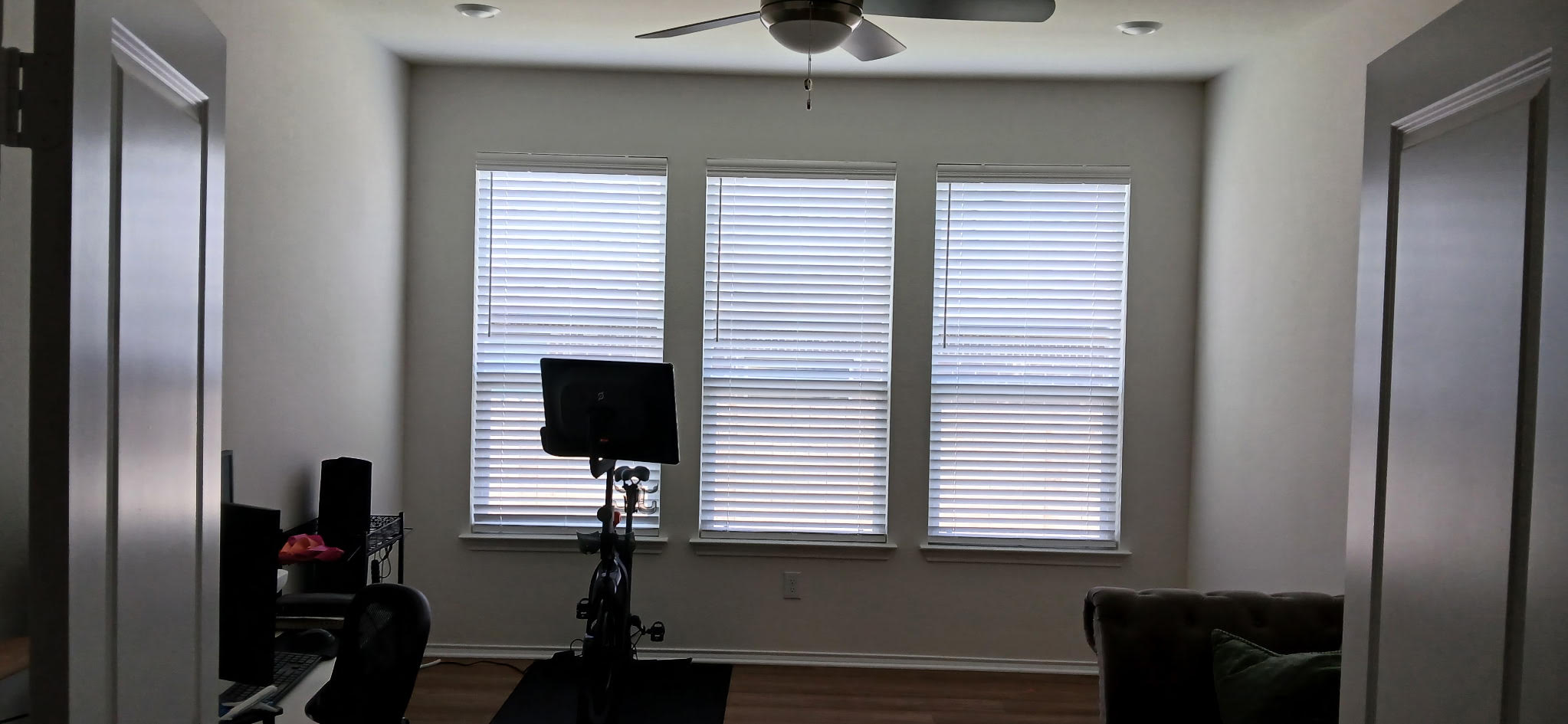 White faux wood blinds on three windows in a home gym