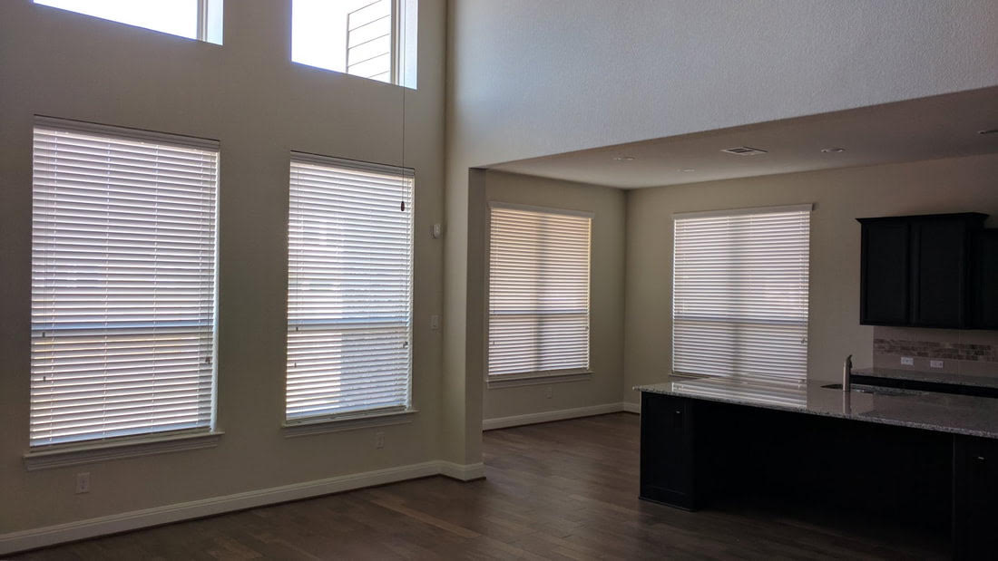 White horizontal blinds across an open-plan living and kitchen area