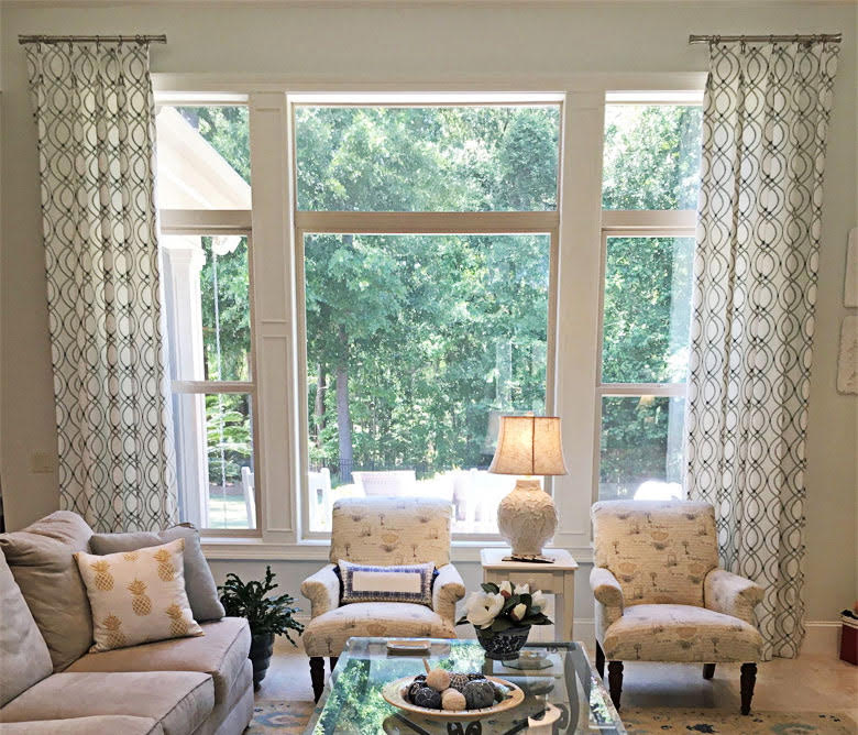Trellis-pattern drapes framing tall windows with a wooded view