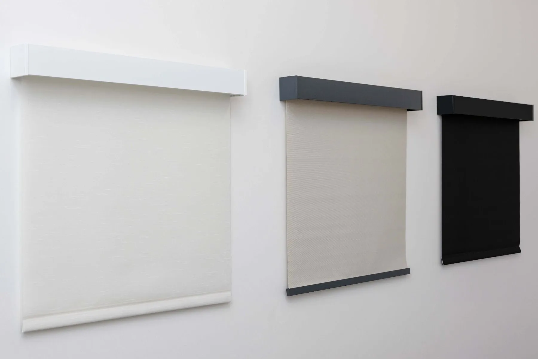 Three roller shade demo panels in white, beige, and black