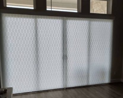 White honeycomb shades covering a sliding glass door
